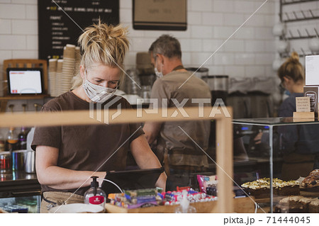 Waitress wearing face mask working in a cafe. 71444045