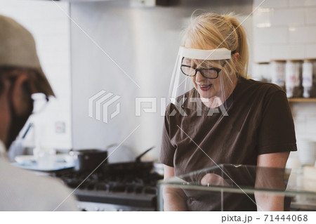 Waitress wearing face mask working in a cafe. 71444068