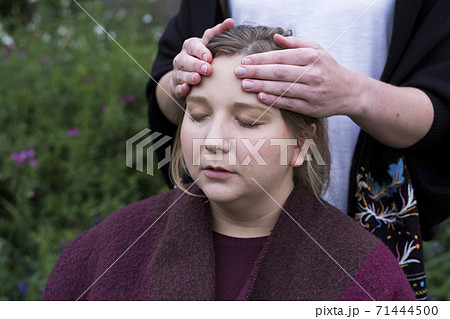 Therapist using both hands touching the top of a client's head. 71444500