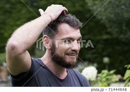 Man sitting in garden tapping his head,  EFT therapy. 71444648