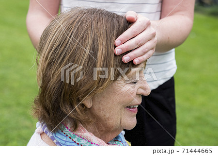 Reiki therapist with a client in a therapy session touching meridian points on the body. 71444665