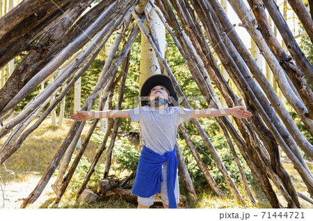 Young boy looking up, standing in a tunnel made of tree logs. Young boy looking up, standing in a tunnel made of tree logs. 71444721
