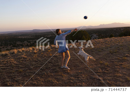 Teenage girl throwing football at sunset. 71444737