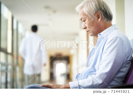 sad and devastated asian senior man sitting alone in hospital hallway, head down sad and devastated asian senior man sitting alone in hospital hallway, head down 71445921