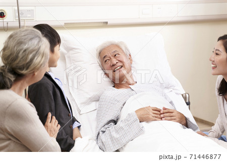 asian old man lying in hospital bed getting a visit from relatives 71446877