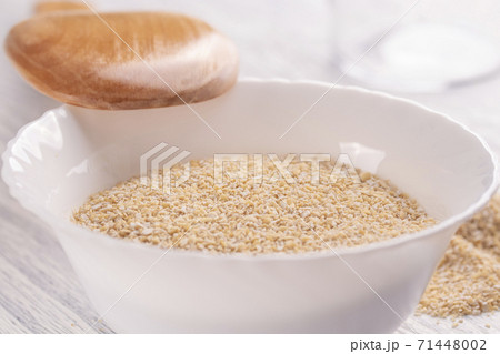 Dry oat bran in a white plate on a light wooden table with a wooden spoon. The concept of useful natural nutrition Dry oat bran in a white plate on a light wooden table with a wooden spoon. The concept of useful natural nutrition 71448002