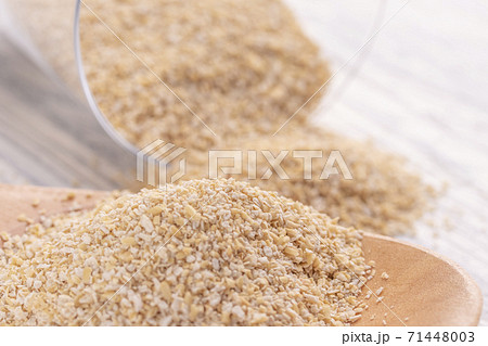 Oat bran in a wooden spoon and in a glass transparent glass on a white wooden table. The concept of good nutrition for weight loss and health Oat bran in a wooden spoon and in a glass transparent glass on a white wooden table. The concept of good nutrition for weight loss and health 71448003