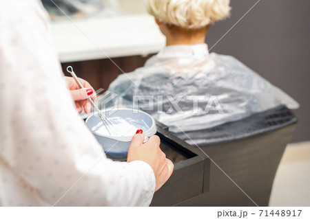 Hairdresser is preparing dye in container Hairdresser is preparing dye in container 71448917