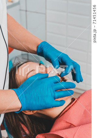 The dentist prepares the patient for the procedure of tartar removal by ultrasound, on the lips of the patient's retractor. 71451456