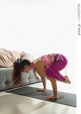 Beautiful young woman working out indoors, doing yoga exercise on gray mat at home 71453759