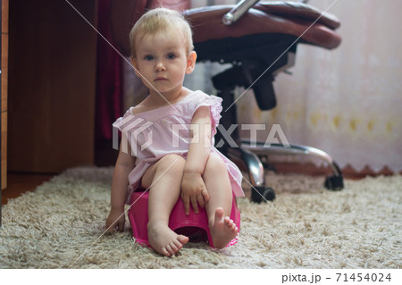 Funny little baby sitting on a pot toilet and pampering Funny little baby sitting on a pot toilet and pampering 71454024