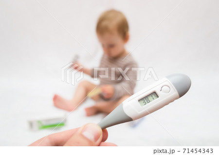 hand holds a thermometer with a high temperature on a white isolated background child with pills hand holds a thermometer with a high temperature on a white isolated background child with pills 71454343