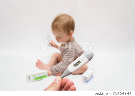 hand holds a thermometer with a high temperature on a white isolated background child with pills 71454344