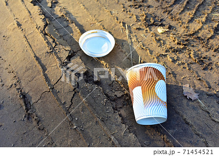 Paper coffee cup on ground. Discarded disposable coffee cup with a plastic lid on road. Paper coffee cup on ground. Discarded disposable coffee cup with a plastic lid on road. 71454521