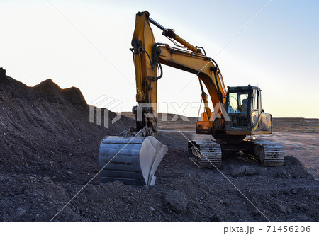 Excavator work at mining quarry on sunset background. Excavator work at mining quarry on sunset background. 71456206