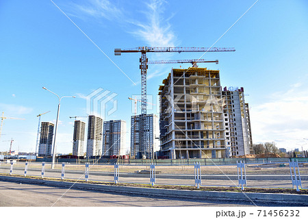 Tower cranes working at construction site on blue sky background. Tower cranes working at construction site on blue sky background. 71456232