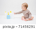 beautiful baby holding a bottle in the hand with shower gel, beside lies Baby cosmetic tubes on white isolated background 71456291