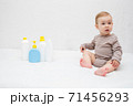 beautiful baby holding a bottle in the hand with shower gel, beside lies Baby cosmetic tubes on white isolated background 71456293