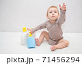 beautiful baby holding a bottle in the hand with shower gel, beside lies Baby cosmetic tubes on white isolated background 71456294