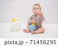 beautiful baby holding a bottle in the hand with shower gel, beside lies Baby cosmetic tubes on white isolated background 71456295