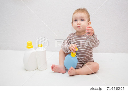 beautiful baby holding a bottle in the hand with shower gel, beside lies Baby cosmetic tubes on white isolated background beautiful baby holding a bottle in the hand with shower gel, beside lies Baby cosmetic tubes on white isolated background 71456295