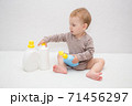 beautiful baby holding a bottle in the hand with shower gel, beside lies Baby cosmetic tubes on white isolated background 71456297