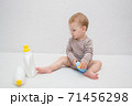 beautiful baby holding a bottle in the hand with shower gel, beside lies Baby cosmetic tubes on white isolated background 71456298