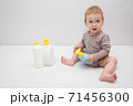 beautiful baby holding a bottle in the hand with shower gel, beside lies Baby cosmetic tubes on white isolated background 71456300
