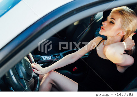 Beautiful blonde woman behind the wheel of car rides Beautiful blonde woman behind the wheel of car rides 71457592