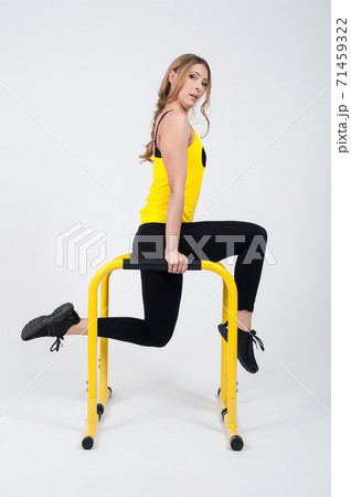 Woman doing exercises with high yellow floor bars on a white background Woman doing exercises with high yellow floor bars on a white background 71459322