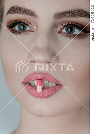Pill between lips. Close up young woman with medicine pill in her sensual mouth 71459919