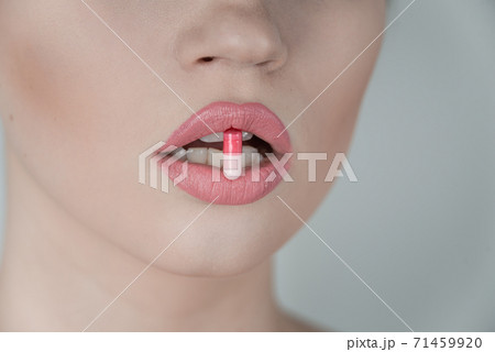 Pill between lips. Close up young woman with medicine pill in her sensual mouth 71459920