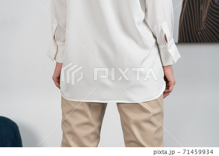 Stylish beautiful young blond woman in a tight biege pants and white shirt near a white wall in the room. Attractive girl model posing. 71459934