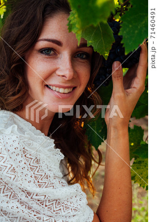 Beautiful fashionable woman in dress collects grapes in vineyards 71460491