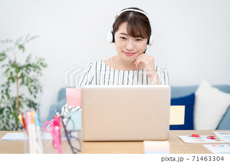 テレワーク　自宅で白いヘッドフォンをつけてウェブ会議をする笑顔の若い女性 71463304