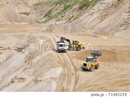 Wheel front-end loader loading sand into heavy dump truck at the opencast mining quarry. Dump truck 71465259