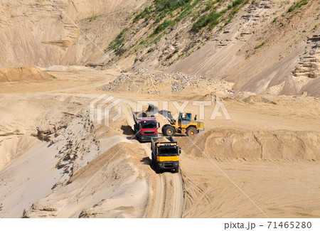 Wheel front-end loader loading sand into heavy dump truck at the opencast mining quarry. Wheel front-end loader loading sand into heavy dump truck at the opencast mining quarry. 71465280