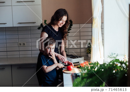 Mom and young son cut fresh vegetables to make salad in the kitchen 71465613