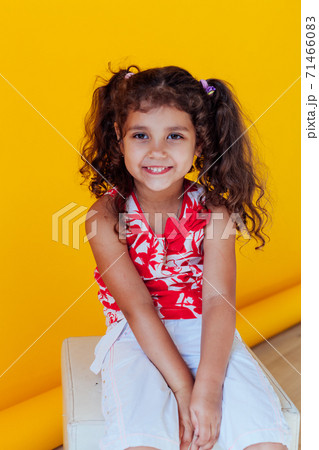 Beautiful little curly cheerful girl with pigtails on a yellow background 71466083