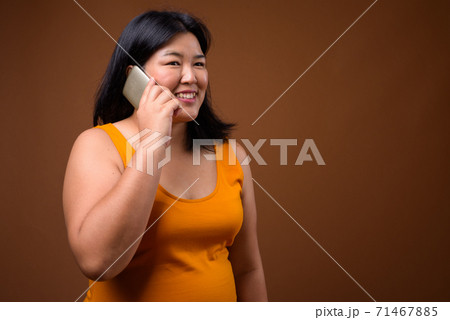 Beautiful overweight Asian woman talking on mobile phone 71467885