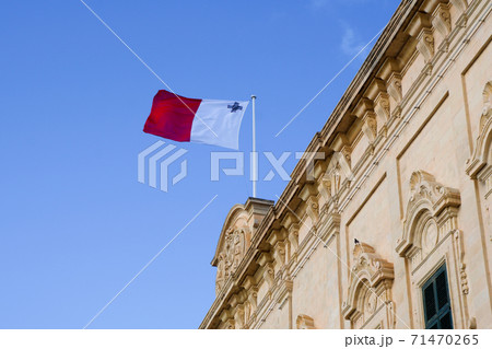 VALLETTA, MALTA - DEC 31st, 2019: Roof of the Auberge de Castille now office of the Prime Minister of Malta topped with a Maltese flag with the coats of arms of Castile and Leon and Portugal 71470265