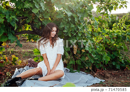 beautiful woman in white dress at a picnic next to the grape tree 71470585