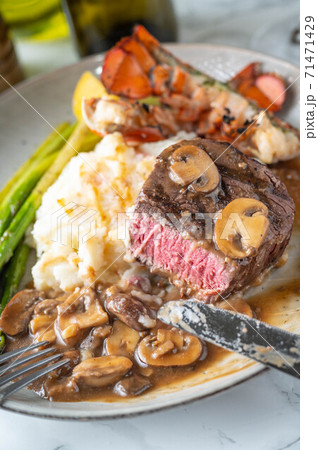eating sruf and turf, tenderloin steak and lobster tail 71471429