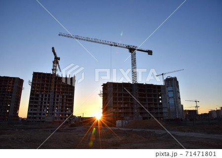 Tower cranes against the blue sky during sunset. Construction of a new high-rise apartment buildings 71471801