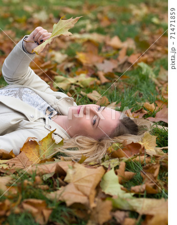 Young Woman Laying in the Grass in Autumn Park Young Woman Laying in the Grass in Autumn Park 71471859