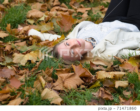 Young Woman Laying in the Grass in Autumn Park Young Woman Laying in the Grass in Autumn Park 71471860