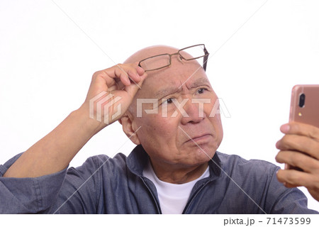 老眼でスマホを操作する日本人シニア男性 老眼でスマホを操作する日本人シニア男性 71473599