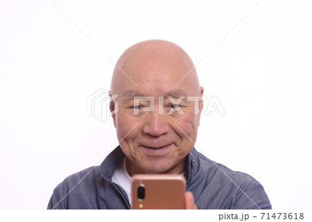 スマホを笑顔で操作する日本人シニア男性 71473618