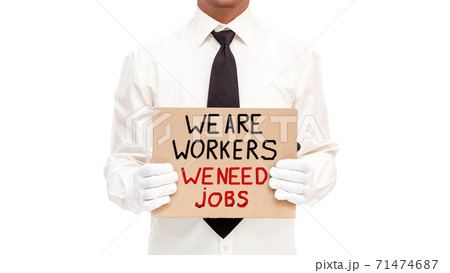 faceless black man in a white shirt with a tie holds in his hands a cardboard poster with the message we are workers we need jobs, unemployed worker isolated on a white background with copy space. faceless black man in a white shirt with a tie holds in his hands a cardboard poster with the message we are workers we need jobs, unemployed worker isolated on a white background with copy space. 71474687