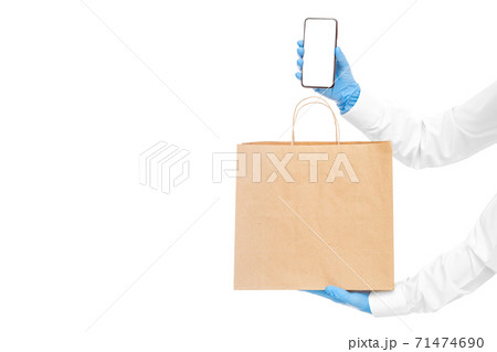 faceless delivery man hold in hands brown paper eco friendly package and cell phone in sterile glove isolated on white with copy space, safe online delivery social distance, stay home. faceless delivery man hold in hands brown paper eco friendly package and cell phone in sterile glove isolated on white with copy space, safe online delivery social distance, stay home. 71474690